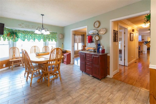 dining space featuring a healthy amount of sunlight, a notable chandelier, light hardwood / wood-style flooring, and a textured ceiling