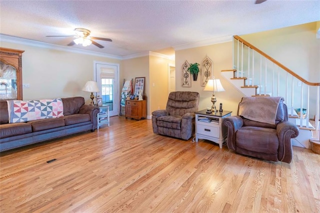 living room with a textured ceiling, light wood-type flooring, ceiling fan, and crown molding