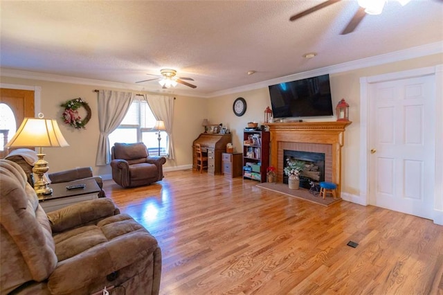 living room featuring ornamental molding, hardwood / wood-style flooring, ceiling fan, and a fireplace