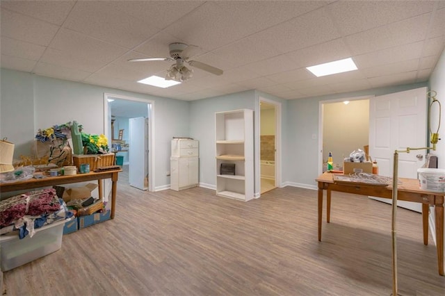 office space with a drop ceiling, wood-type flooring, and ceiling fan