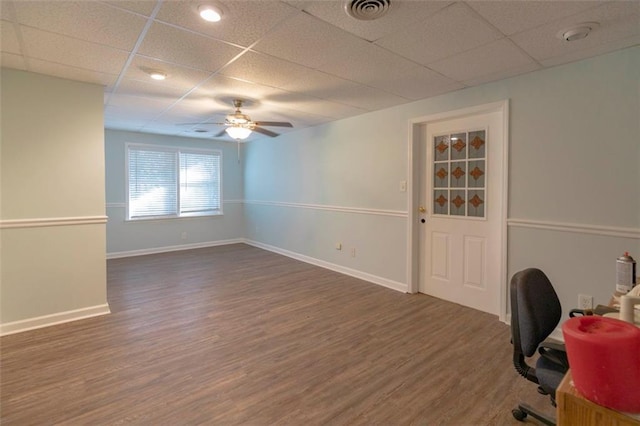 unfurnished office featuring a drop ceiling, dark hardwood / wood-style flooring, and ceiling fan