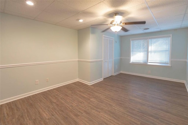 unfurnished room featuring ceiling fan, dark hardwood / wood-style floors, and a drop ceiling