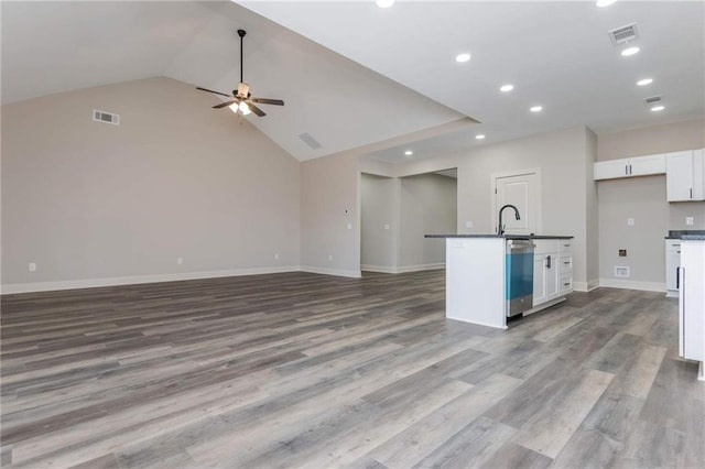 kitchen with vaulted ceiling, sink, white cabinets, ceiling fan, and light hardwood / wood-style flooring