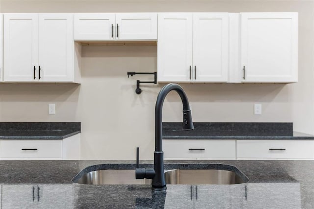 kitchen with sink, dark stone countertops, and white cabinets