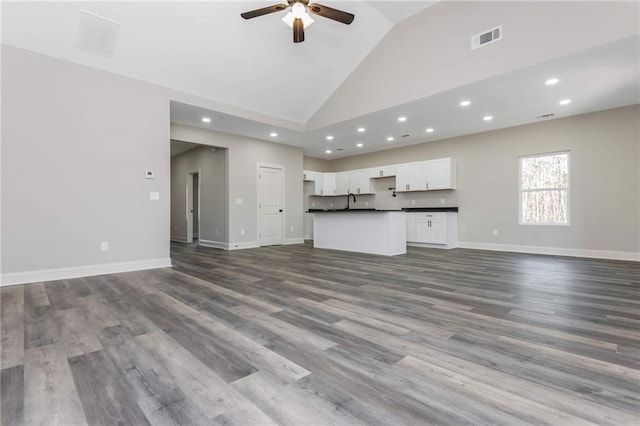 unfurnished living room featuring ceiling fan, wood-type flooring, sink, and high vaulted ceiling