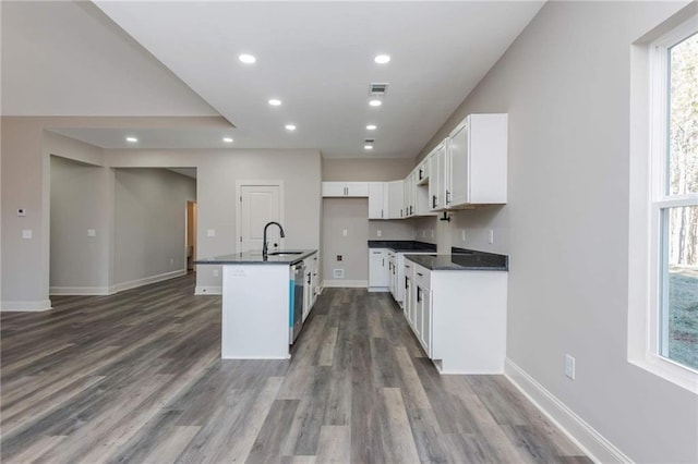 kitchen with sink, white cabinetry, dark hardwood / wood-style floors, dishwasher, and a kitchen island with sink