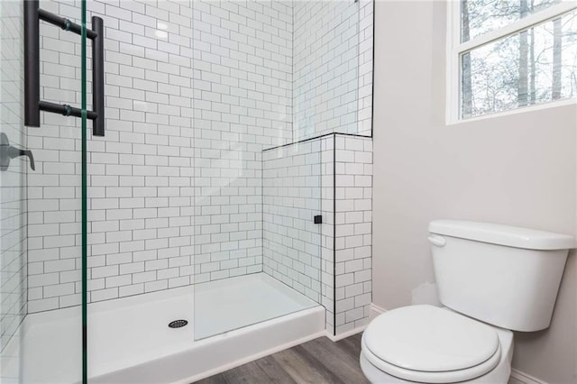 bathroom featuring wood-type flooring, toilet, and a shower with shower door