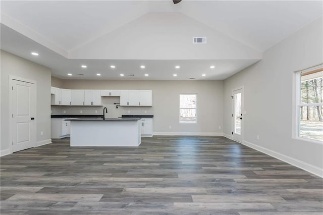 kitchen with white cabinetry, a wealth of natural light, a kitchen island with sink, and dark wood-type flooring