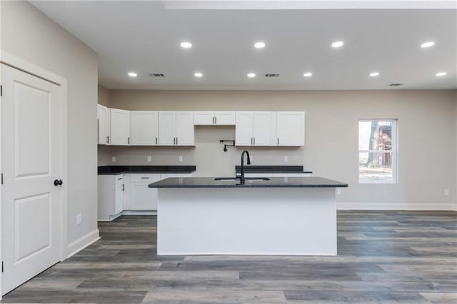 kitchen featuring a kitchen island with sink, sink, and white cabinets