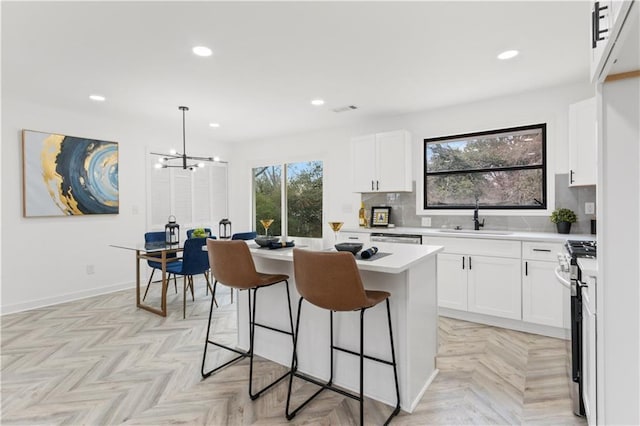1066 Cleavemark Dr, Clarkston, GA 30021 - kitchen with a sink, a kitchen breakfast bar, light countertops, white cabinetry, and backsplash