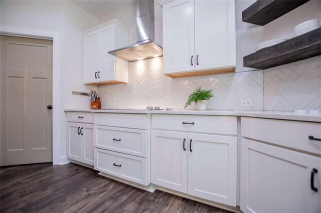 kitchen with dark hardwood / wood-style flooring, wall chimney range hood, white cabinetry, and tasteful backsplash