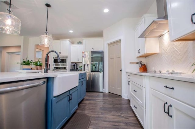 kitchen with blue cabinets, stainless steel appliances, hanging light fixtures, and white cabinetry