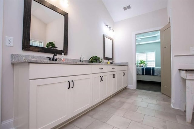 bathroom with tile patterned flooring, vanity, and vaulted ceiling