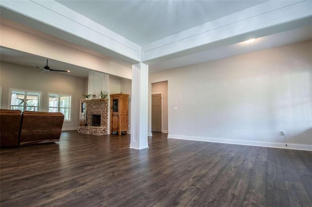 living room featuring ceiling fan, a brick fireplace, dark hardwood / wood-style flooring, and decorative columns