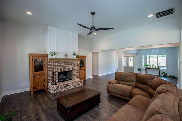 living room featuring dark wood-type flooring, ceiling fan, and a fireplace