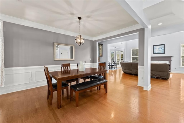 dining room featuring a chandelier, french doors, ornamental molding, and light wood-type flooring