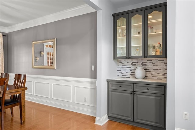 dining area with bar area, light hardwood / wood-style flooring, and ornamental molding