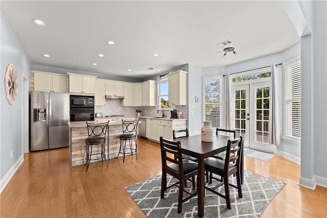 dining space with sink, light hardwood / wood-style floors, and french doors