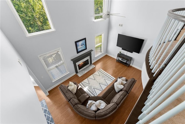 living room with ceiling fan, hardwood / wood-style floors, and a towering ceiling