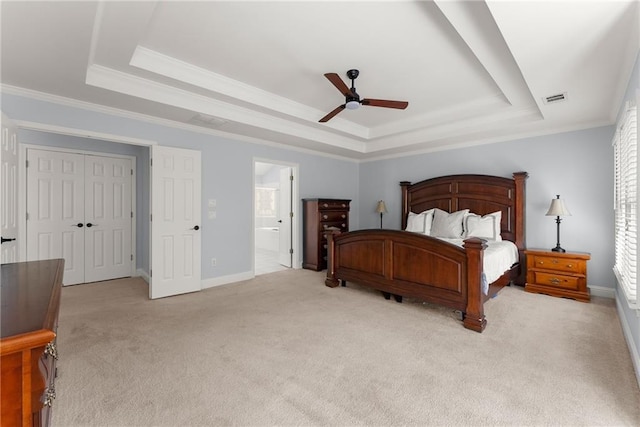 carpeted bedroom featuring ensuite bathroom, a raised ceiling, crown molding, ceiling fan, and a closet