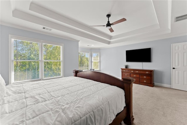 bedroom featuring light carpet, a tray ceiling, ceiling fan, and crown molding