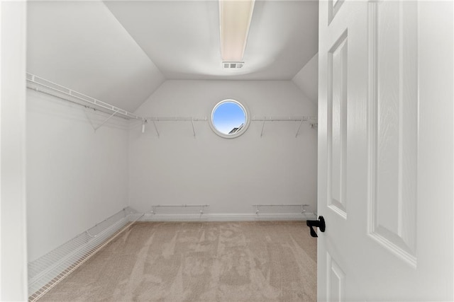 walk in closet featuring light colored carpet and lofted ceiling