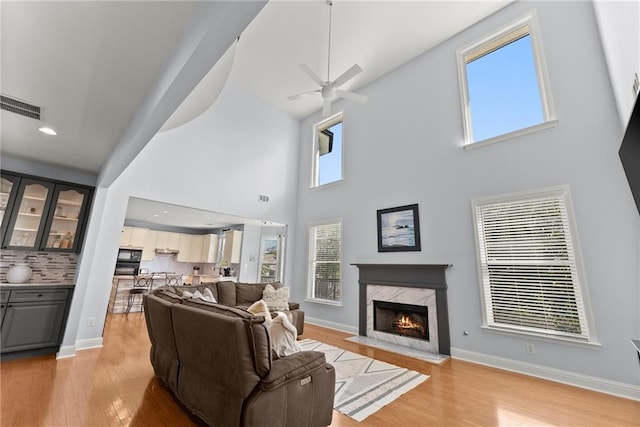 living room featuring light hardwood / wood-style flooring, a towering ceiling, and a healthy amount of sunlight