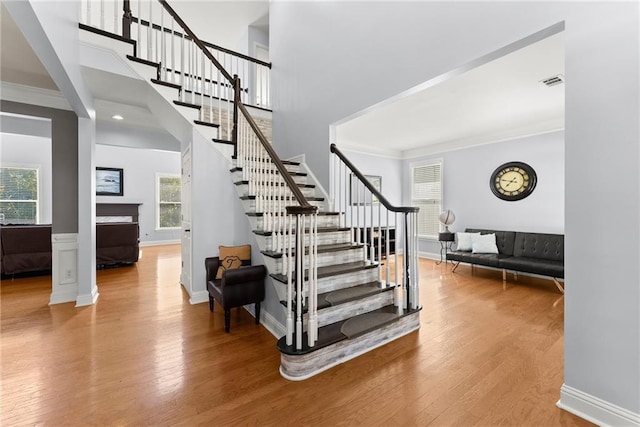 stairway with ornamental molding, a healthy amount of sunlight, and hardwood / wood-style flooring