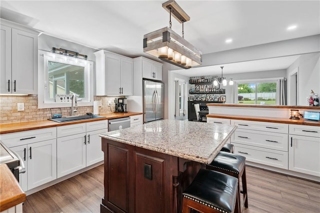 2545 Hickory Level Rd, Villa Rica, GA 30180 - kitchen with a sink, appliances with stainless steel finishes, a center island, tasteful backsplash, and light wood-type flooring