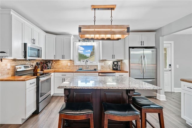 2545 Hickory Level Rd, Villa Rica, GA 30180 - kitchen with appliances with stainless steel finishes, a sink, a breakfast bar area, and light wood finished floors