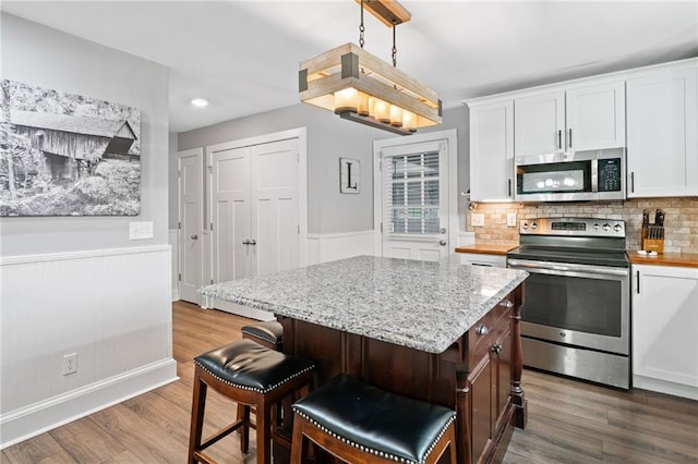 2545 Hickory Level Rd, Villa Rica, GA 30180 - kitchen featuring appliances with stainless steel finishes, dark wood-style flooring, a wainscoted wall, white cabinets, and light stone counters