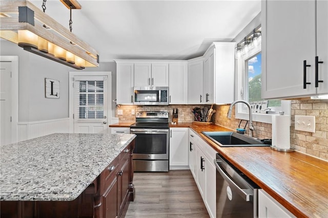 2545 Hickory Level Rd, Villa Rica, GA 30180 - kitchen featuring stainless steel appliances, a sink, white cabinets, light stone counters, and wainscoting