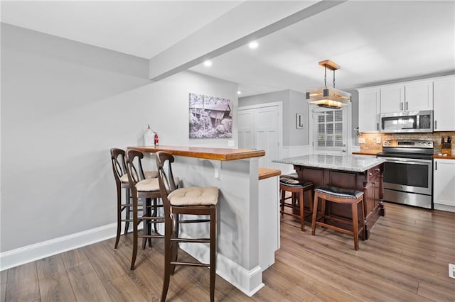 2545 Hickory Level Rd, Villa Rica, GA 30180 - kitchen featuring appliances with stainless steel finishes, recessed lighting, a kitchen breakfast bar, white cabinets, and decorative backsplash