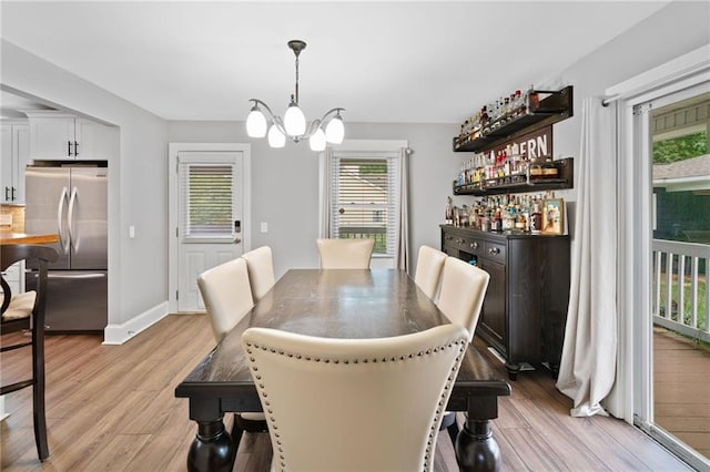 2545 Hickory Level Rd, Villa Rica, GA 30180 - dining space with a chandelier, light wood-type flooring, a bar, and baseboards