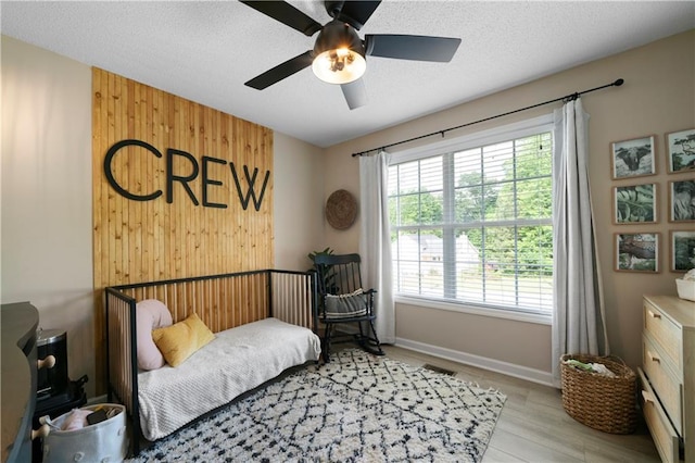 71 Headland Ct, Rockmart, GA 30153 - bedroom with light wood-type flooring, baseboards, wooden walls, ceiling fan, and a textured ceiling