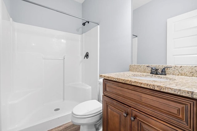 bathroom with a shower, hardwood / wood-style floors, vanity, and toilet