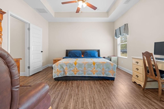 bedroom featuring ceiling fan, wood-type flooring, and a tray ceiling