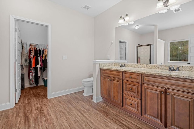 bathroom featuring vanity, hardwood / wood-style flooring, toilet, and a shower with door