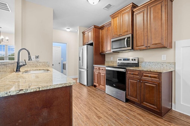 kitchen with a chandelier, sink, light hardwood / wood-style floors, and appliances with stainless steel finishes