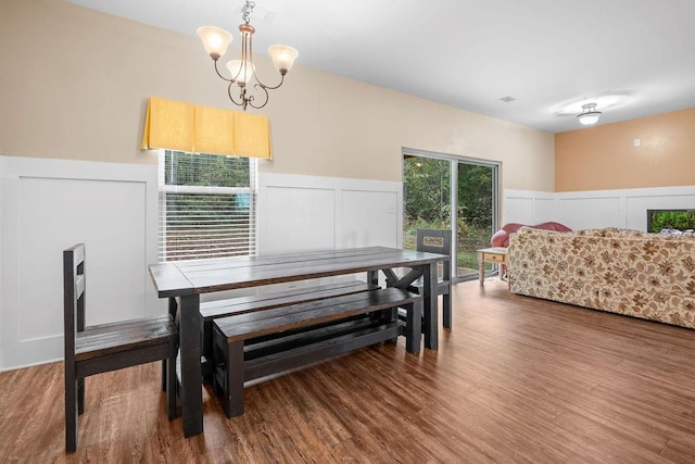 dining space featuring hardwood / wood-style flooring and an inviting chandelier