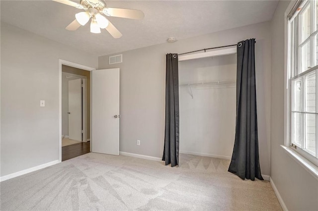 unfurnished bedroom with ceiling fan, a closet, and light colored carpet