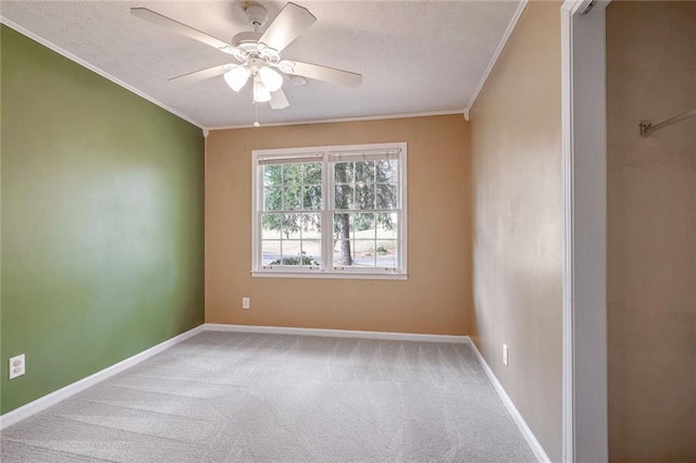 empty room featuring a textured ceiling, ceiling fan, crown molding, and light carpet