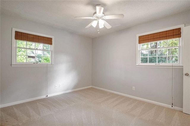 empty room with light carpet, ceiling fan, and a healthy amount of sunlight