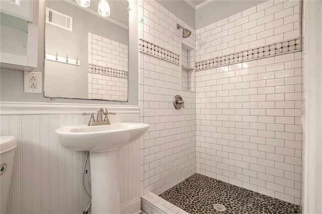 bathroom featuring tiled shower and toilet