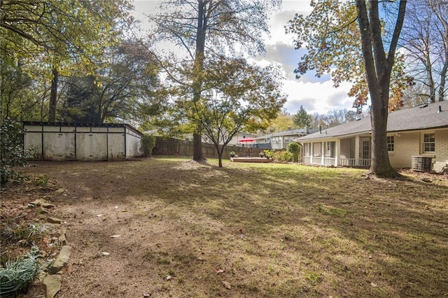 view of yard with central air condition unit, a sunroom, and a swimming pool