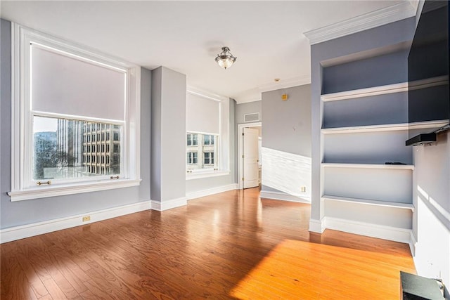 unfurnished living room featuring built in shelves, wood-type flooring, and ornamental molding