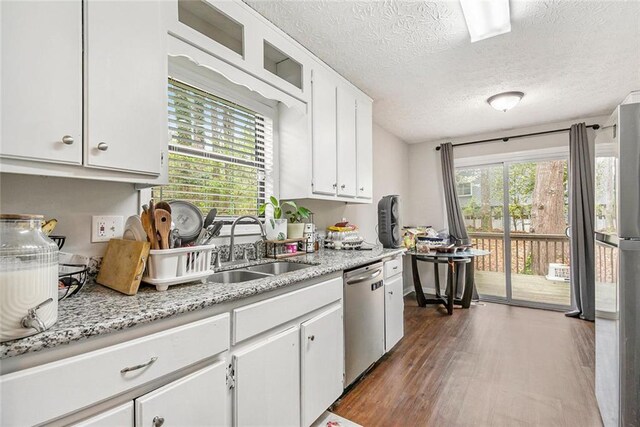 kitchen featuring a sink, a textured ceiling, stainless steel appliances, white cabinets, and dark wood-type flooring