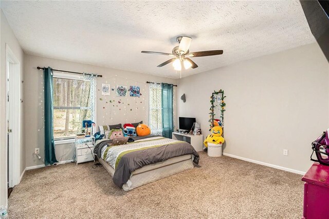 carpeted bedroom with a ceiling fan, baseboards, multiple windows, and a textured ceiling