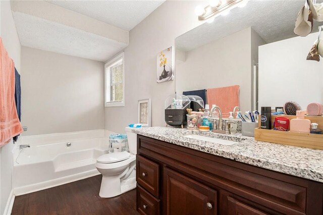 full bathroom featuring vanity, a textured ceiling, a garden tub, and wood finished floors