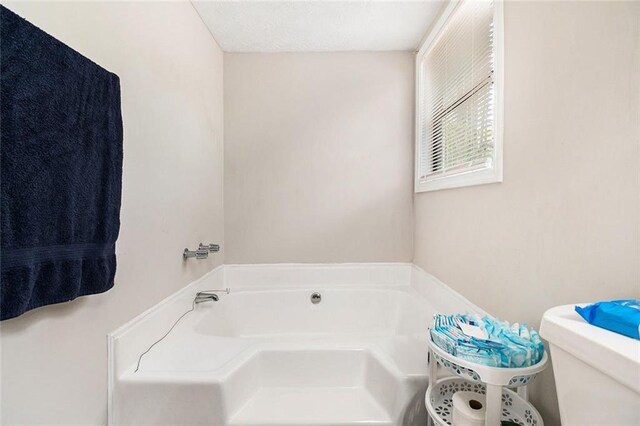 bathroom with toilet and a garden tub